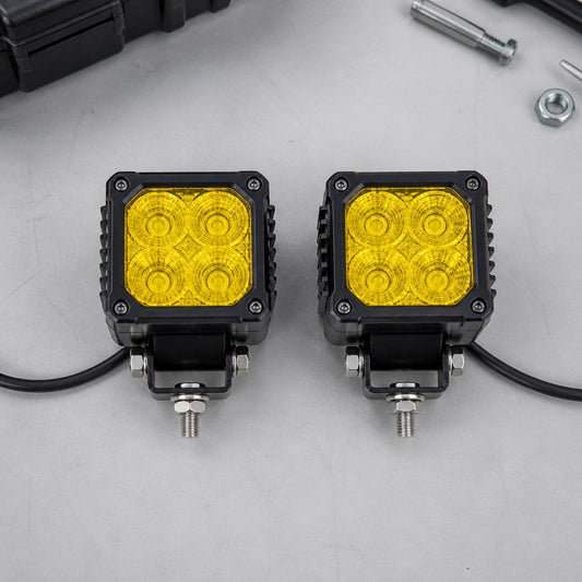 Pair of yellow-lens cube work lights on a dark workbench