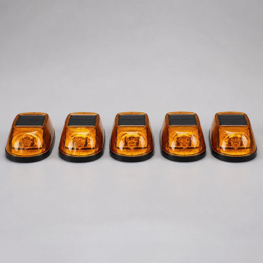 Five amber cab roof marker lights lined up on a workbench