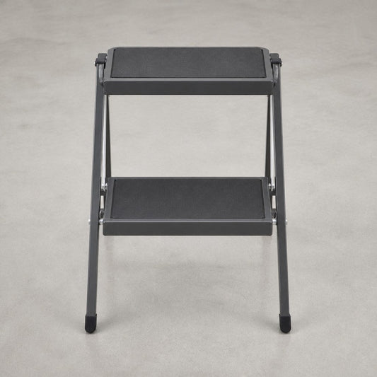 Compact folding steel step stool open on a shop floor