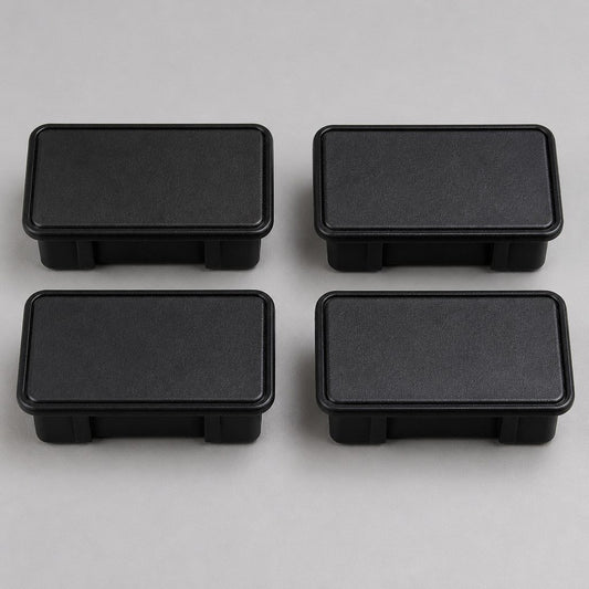 Four black plastic bed stake-pocket covers on a workbench